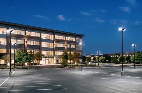 Commercial building and parking lot illuminated by LED area lights at dusk.