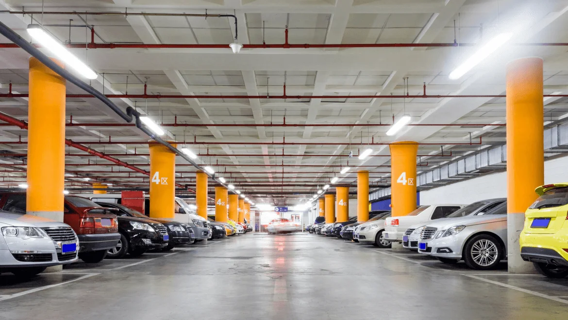 Parking intérieur éclairé avec des voitures et poteaux oranges